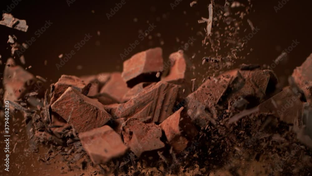 Poster super slow motion of flying group of raw chocolate pieces with cocoa powder. filmed on high speed ci