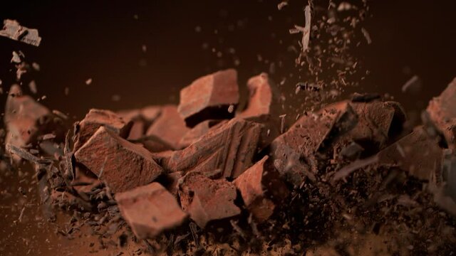 Super slow motion of flying group of raw chocolate pieces with cocoa powder. Filmed on high speed cinema camera, 1000fps.
