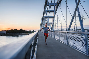 Sports man running fast outdoors on a race track