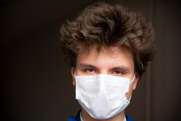 Portrait of a teenage boy in a protective mask on an abstract background.