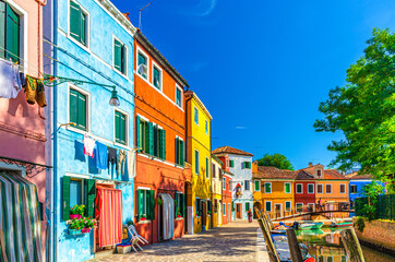 Plakat Colorful houses of Burano island. Multicolored buildings on fondamenta embankment of narrow water canal with fishing boats and wooden bridge, Venice Province, Veneto Region, Northern Italy