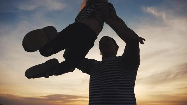 dad and daughter play in the park happy family. kid dream concept happy family playing. dad and daughter lifts her into the air play the pilot hands to fun the sides plane. happy family in the park