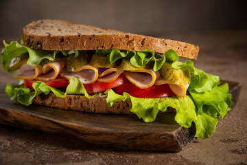 Sandwich made from rustic rye bread, lettuce, tomato and ham