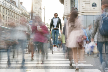 Jeune homme en apesanteur au milieux d'une foule dans une rue