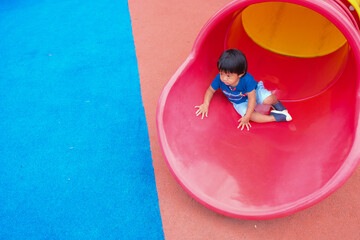 Little boy playing on playground park enjoying slider