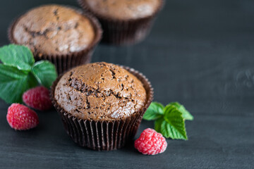 Chocolate muffins with raspberries on dark wooden background, selective focus