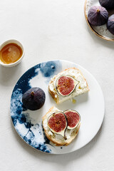 Two Sandwich with Ricotta and fresh Figs sprinkled honey on plate on grey concrete background. Simple healthy breakfast
