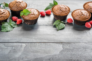 Chocolate muffins with raspberries on dark wooden background, selective focus, horizontal orientation, copyspace