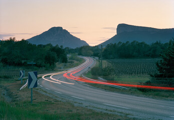 feux de voiture sur une route du sud de la France à la tombée de la nuit à côté du pic saint loup