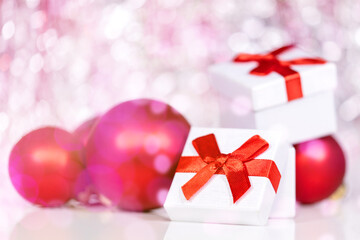 Presents and red baubles with pink and white shiny background