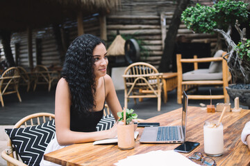 Cheerful woman with laptop in outdoor cafe