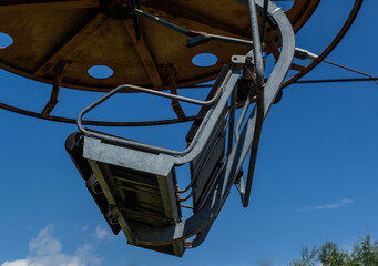 old cable car round circle construction with gray seat, sunny summer sky with white clouds