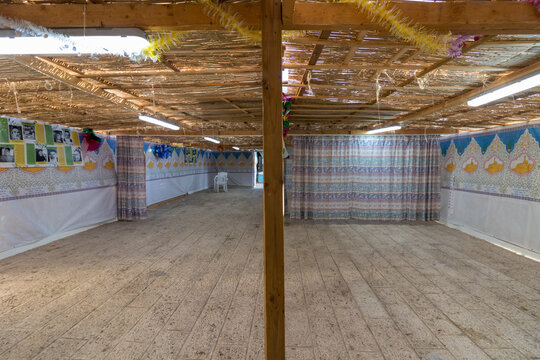 An inside view of an ornate sukkah, a Jewish building for sitting on Sukkot