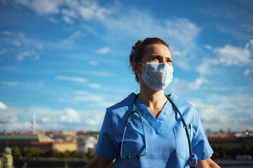 modern medical doctor woman in uniform outside against sky - obrazy, fototapety, plakaty