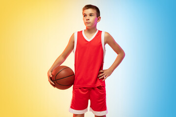 Full length portrait of young basketball player in uniform on gradient studio background. Teenager...
