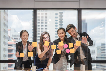 Multi ethnic business team brainstorming with post it note paste up on conference board in coworking space