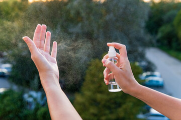 Women using an alcohol hand sanitizer from a spray bottle for cleaning hands and palms protection from viruses, Covid-19 and coronavirus	