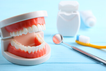 model of teeth and dental instruments and dental care products on colored background