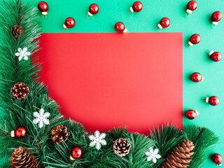 Fototapeta na wymiar New year or Christmas layout, flatly, copy space. Christmas frame of Christmas trees and decorations on a green background, place for text on a red background. Layout for a greeting card