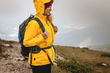 Woman hiking at mountains in extreme weather. Tourist wearing waterproof jacket with hood. 