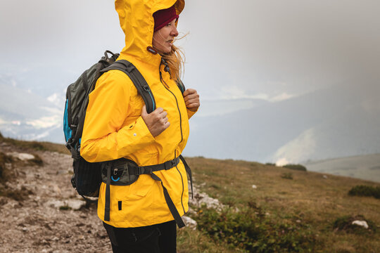 Woman Hiking At Mountains In Extreme Weather. Tourist Wearing Waterproof Jacket With Hood. 