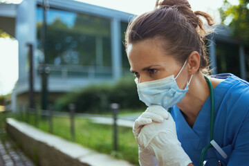 unhappy modern medical doctor woman sitting outside near clinic