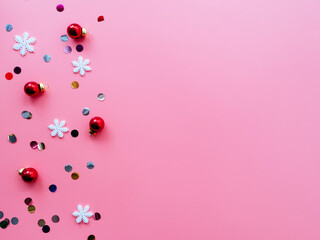 Snowflakes, confetti and red Christmas balls on a pink background, flatly, copyspace. Bright Christmas holiday concept. New year's layout or Christmas background
