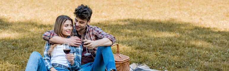 horizontal image of man and woman holding glasses with red wine during picnic