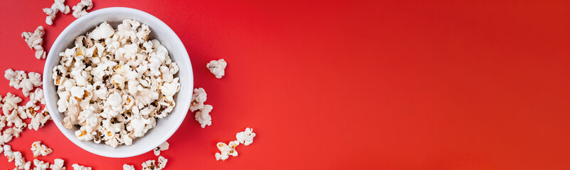 Bowl of popcorn on red background, top view