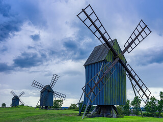 Three traditional windmills in a thunderstorm atmosphere in the village of Resmo, Oland, Sweden,...