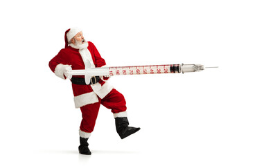 Santa Claus holding huge vaccine against COVID like Christmas gift isolated on white background. Male model in traditional costume. New Year, holidays, winter, epidemic, pandemic concept. Copyspace.