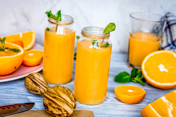 Obraz na płótnie Canvas healthy orange cocktail with mint leaves in bottle on kitchen background