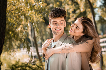 joyful woman hugging boyfriend in autumnal park