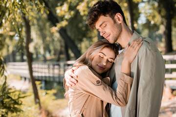 couple with closed eyes hugging in autumnal park