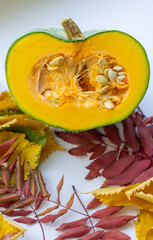 Cut ripe, yellow pumpkin on a wooden background with autumn leaves.