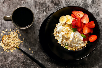 Healthy breakfast. Cottage cheese with sour cream or yogurt, oatmeal, banana and strawberry on a dark background
