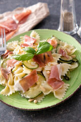 Tasty farfalle pasta with courgette, prosciutto ham, grana padano cheese and pine nuts