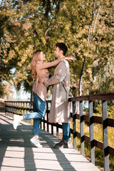 side view of excited couple hugging while standing on wooden bridge