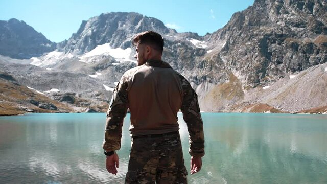 A special forces soldier in a multicam climbed to the top of the mountain to the reservoir