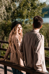 Fototapeta premium blonde woman in hat looking at boyfriend in trench coat