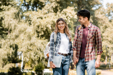 woman with laptop holding hands with man in park