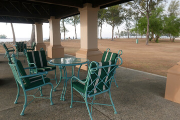 Obraz premium A set of an empty green chair and table by the beach for hangout or discussion during leisure time