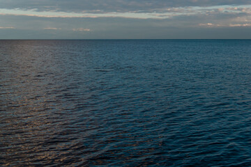 Obraz premium view of the clear calm undulating .ripples water of Lake Baikal, sunset clouds on the horizon, sky background