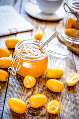 kumquat on plate and jam in jar at wooden table