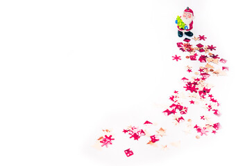 Red and orange shiny confetti, Christmas background. Small Santa figure and sequins on a white background. Happy new year and merry Christmas.