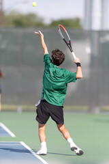 Boy serving the ball during a tennis match
