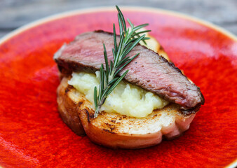 Grilled beef cooked medium-rare on creamy mash crostini.