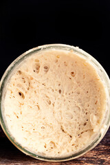 Detail of overturned jar of wholemeal sourdough on dark background