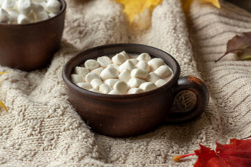 Obraz na płótnie Canvas A cup of hot cocoa with marshmallows stands on a cozy knitted blanket. Autumn, Thanksgiving concept.
