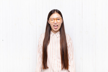 asian young woman with cheerful, carefree, rebellious attitude, joking and sticking tongue out,...